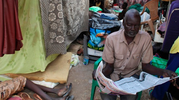 A displaced man reads a newspaper at Tomping camp, where some 17,000 displaced people are being sheltered by the UN, in Juba